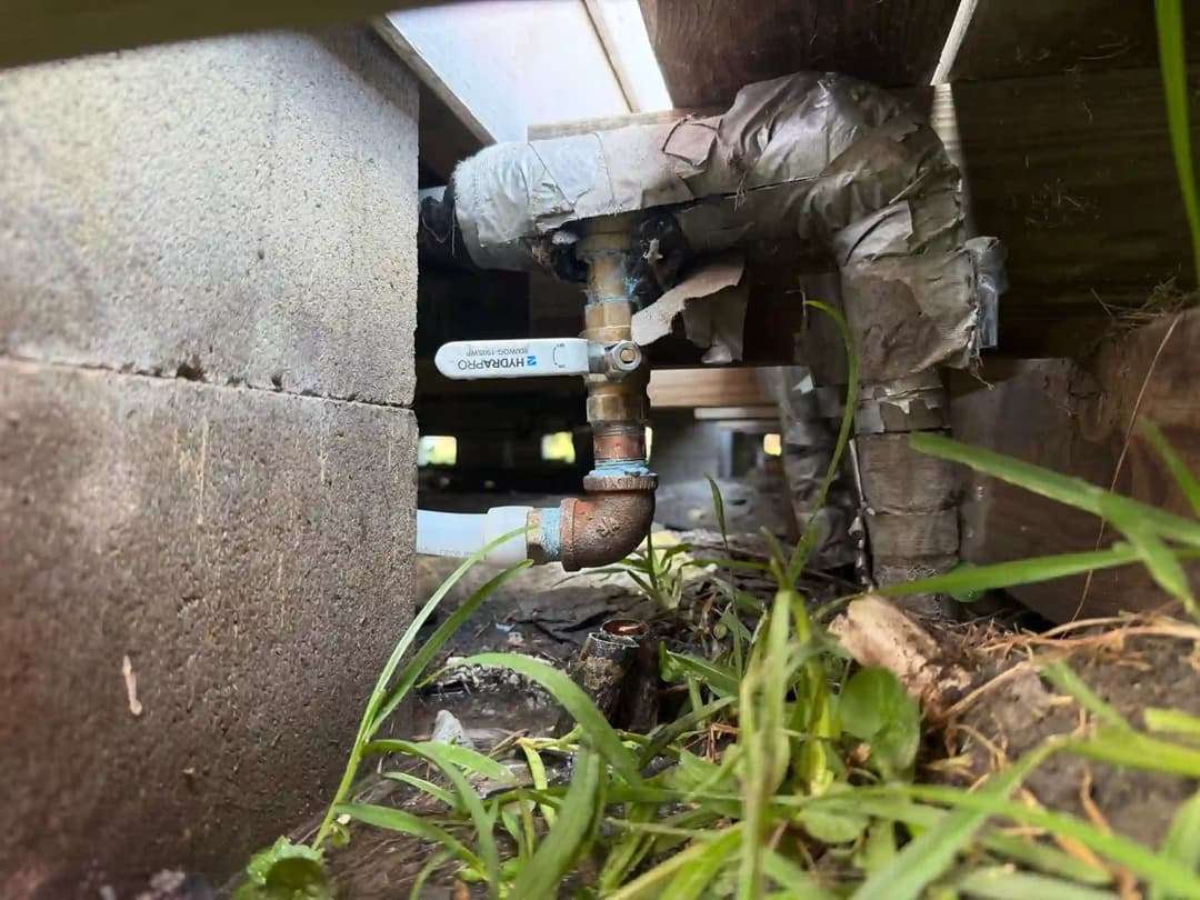 Underground water valve with plumbing tape and grass nearby in a residential setting.