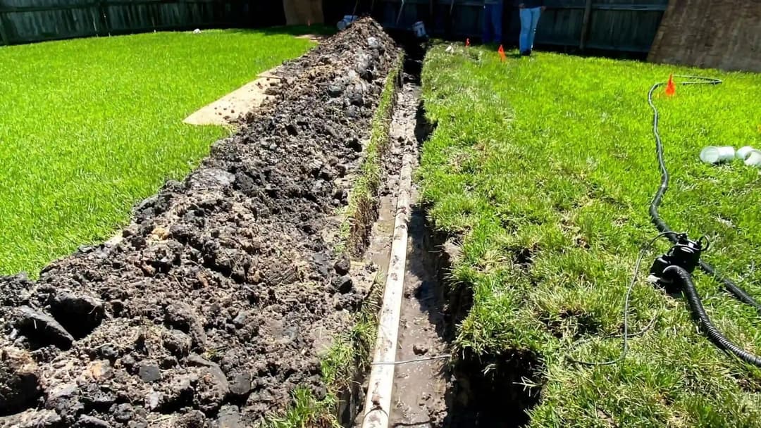 Excavated trench in a grassy yard for utility installation or landscaping project.